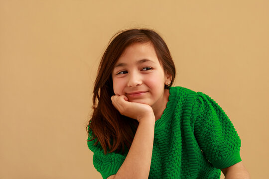 Girl Smiles While Resting Her Chin on Her Hand in a Room