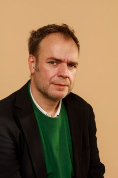 Man Poses for a Portrait Against a Plain Background