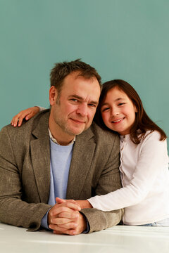 Man and Girl Sit Together With Smiles in a Studio Setting