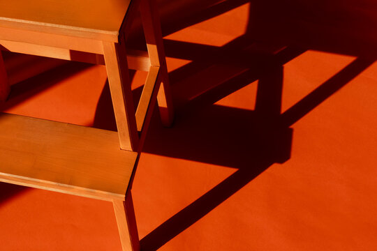 Shadows of Wooden Stools on Orange Floor at Sunny Afternoon
