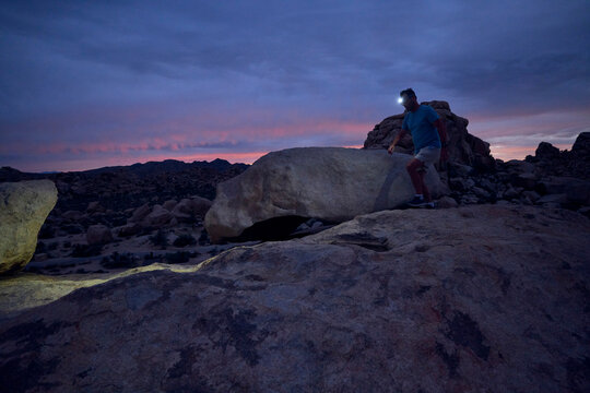 Man Hiking at Night With a Headlamp in Rocky Landscape