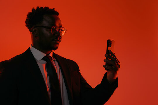 Businessman in Suit Checking Smartphone Against Red Background