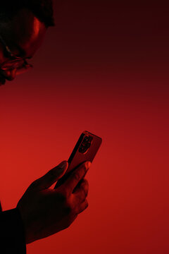 Man Using Smartphone Under Dramatic Red Lighting