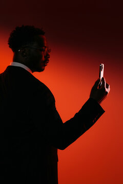 Businessman Silhouette Holding Smartphone Against Red Background