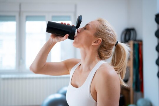 Woman sips water at gym
