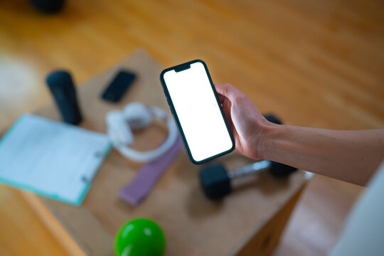 Holding smartphone with blank screen above workout equipment