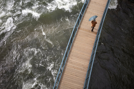 Person with Umbrella Crossing Footbridge Over River