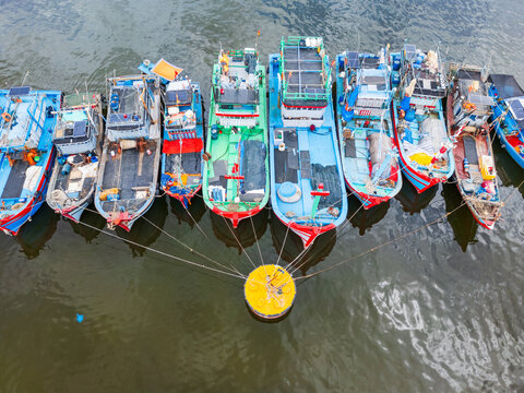 Colorful fishing boats moored in a line around a docking bouy