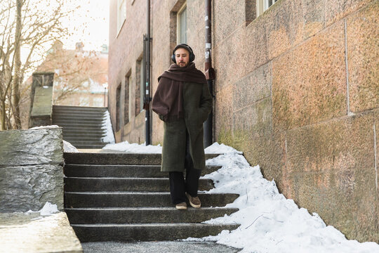 Man in winter coat and headphones walking through urban city