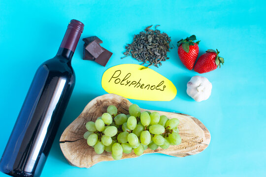 Products containing many different beneficial polyphenols in their composition. Grapes, red wine, garlic, chocolate, green tea, nuts, strawberries close-up on a light background and the inscription on