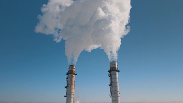 Passing between two smoke stacks as they belch white cloud into the sky