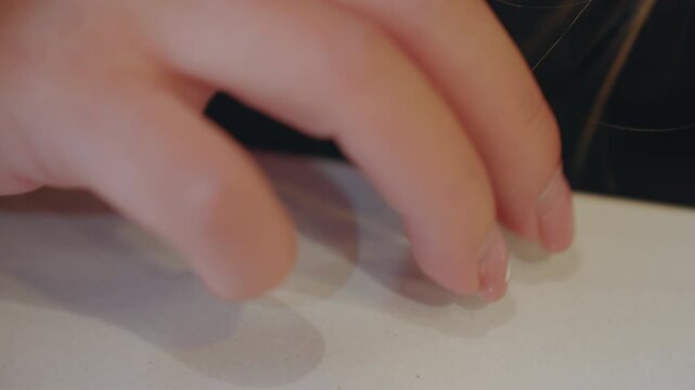 Closeup caucasian child fingertip on table, stealthy reach across white surface, chipped manicure, soft shadow, anxious motion, implied snatcher action, slow careful retrieval, low ambient light,