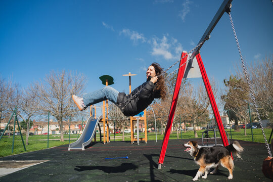 Joyful person swinging high with playful dog in park