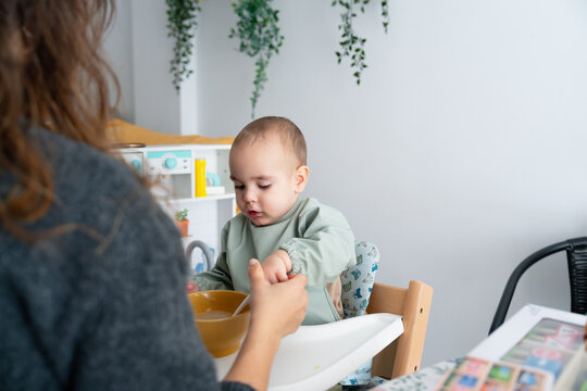 Mother helping youngster eat in cozy home setting