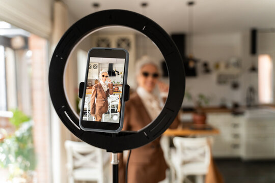Senior woman recording shopping vlog at home