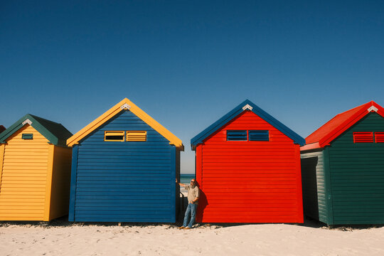 Bearded man posing at colorful beach huts in Muizenberg
