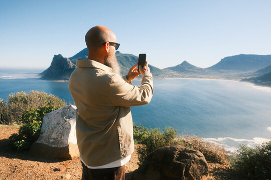 Bearded man taking photo of coastal landscape in Cape Town
