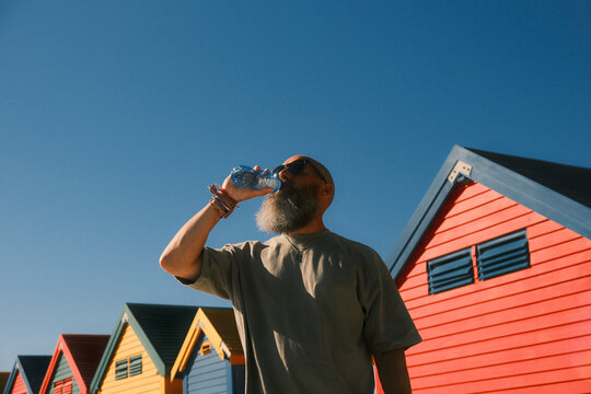 Bearded man drinking water at Muizenberg beach huts