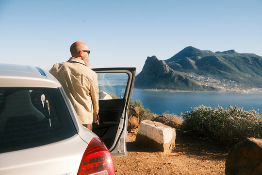 Bearded man wearing sunglasses standing behind car in Cape Town
