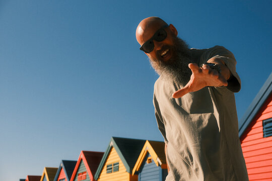 Bearded man posing at colorful beach huts in Muizenberg
