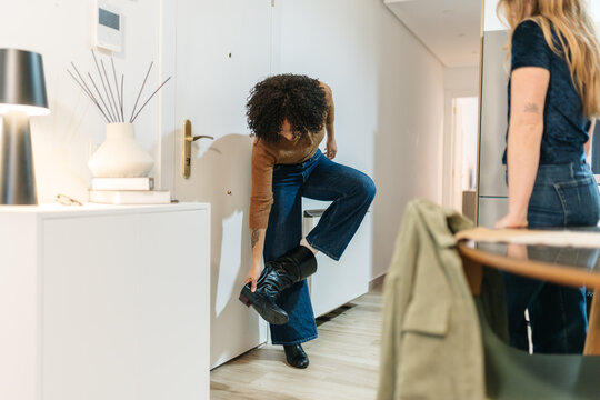 Friend arriving home taking off boots