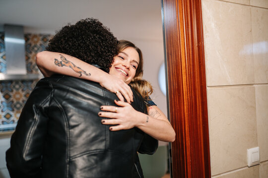 Friends hugging arriving home for a visit