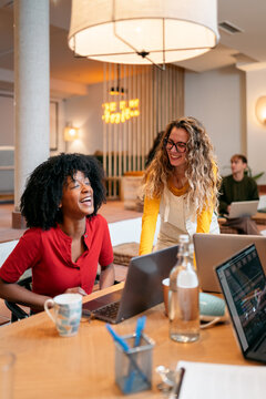 Diverse young women collaborating laughing in coworking space