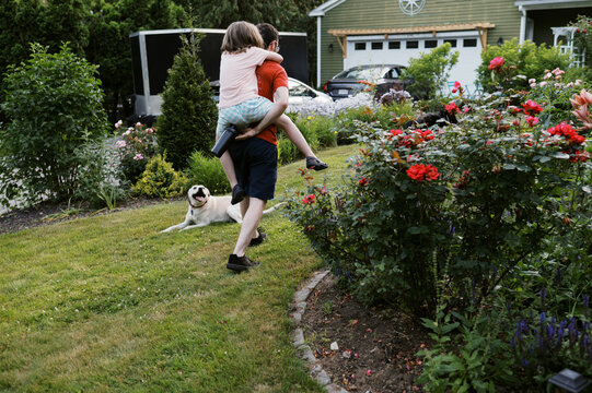 Happy father and daughter playing in yard with their dogs