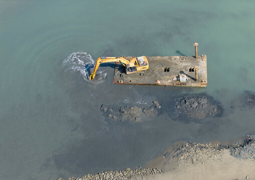 Excavator Dredging Silt and Sediment in Coastal Harbor