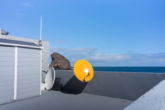 Satellite dish facing ocean horizon 