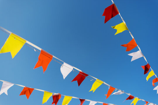 Colorful Flags Hang in Clear Blue Sky During Outdoor Celebration