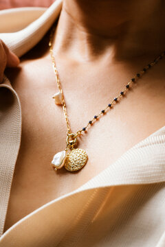 Woman's neck with a pearl charm necklace with beaded chain