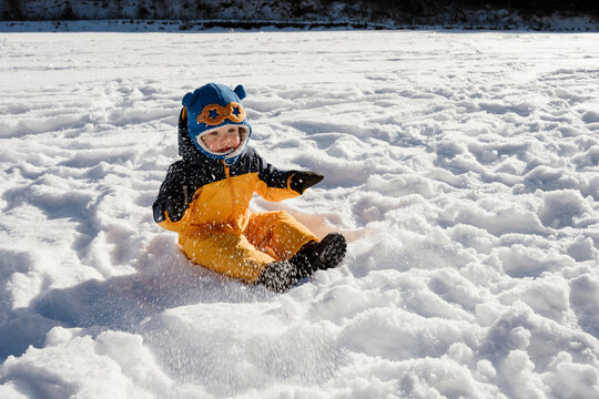 A toddler sitting on fresh snow and having fun
