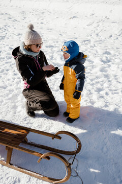A toddler and his mom are together in thesnow in winter