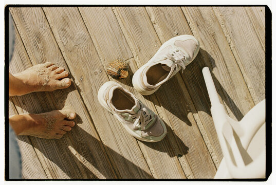 Bare feet and sneakers on wooden boardwalk