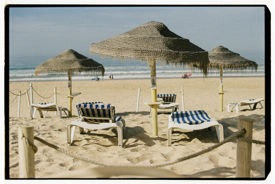 Empty sun loungers under straw umbrellas