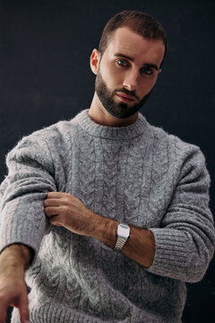 Man Adjusting Sweater Sleeve While Posing in Studio