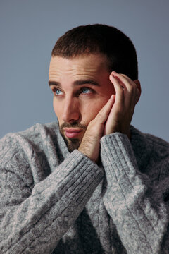 Man Sits With Hands on Face in a Light Blue Background
