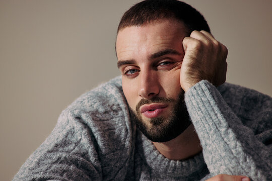 Young Man Poses With Hand on Face in Studio Setting