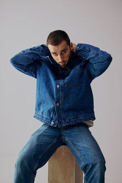 Man Adjusts His Jacket While Seated on a Pedestal