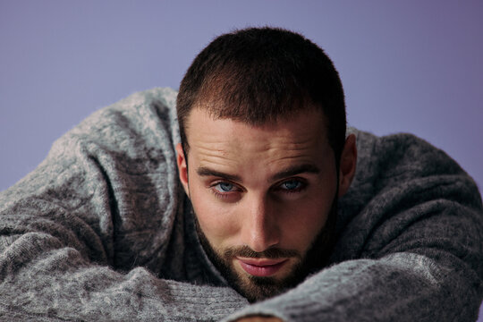 Man Resting on a Table Wearing a Gray Sweater With Focused Expression