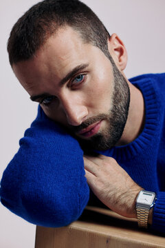 Man Resting His Chin on Hand While Wearing a Blue Sweater