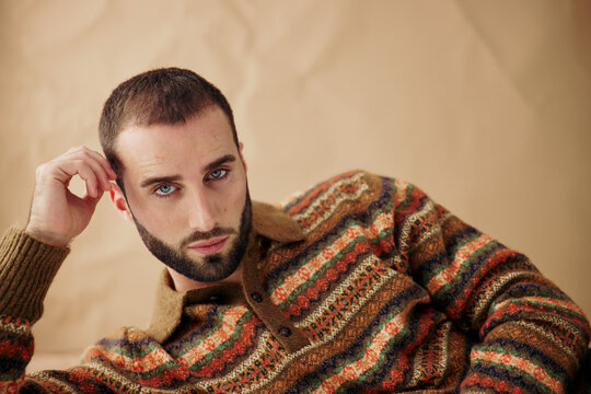 Young Man Poses in a Colorful Sweater Against a Neutral Background