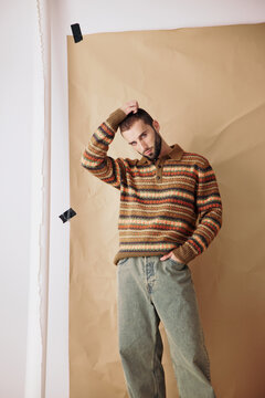 Man in Sweater Poses in Studio With Brown Backdrop and Natural Light