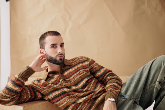 Man Posing on a Wooden Surface With a Neutral Background
