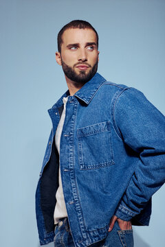 Man Poses in Denim Jacket Against Light Blue Background