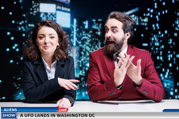Presenters team reveals ufo landing in washington, talking about alien invasion in usa while broadcasing live in newsroom. Man and woman journalists reporting latest national information. © DC Studio