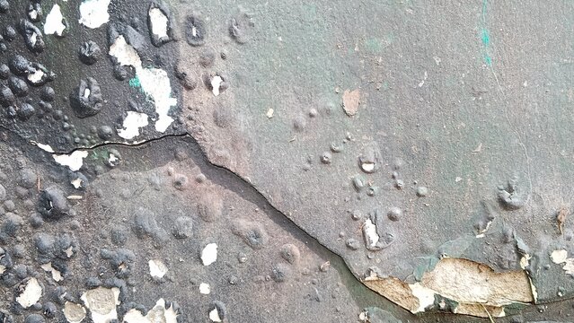 Close-up of a weathered green painted surface with peeling paint and rough texture