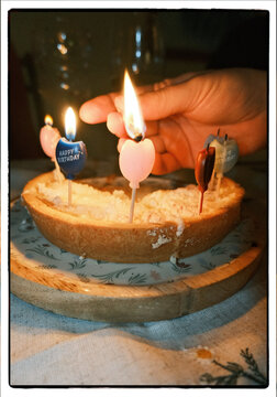 Lighting heart shaped birthday candles on homemade cake
