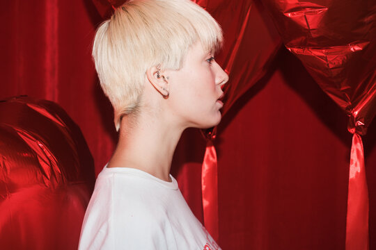 Profile View of Person Against Red Backdrop With Balloons